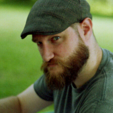 A headshot of Andrew Hay, the art director of The Keep Studios, in a cap